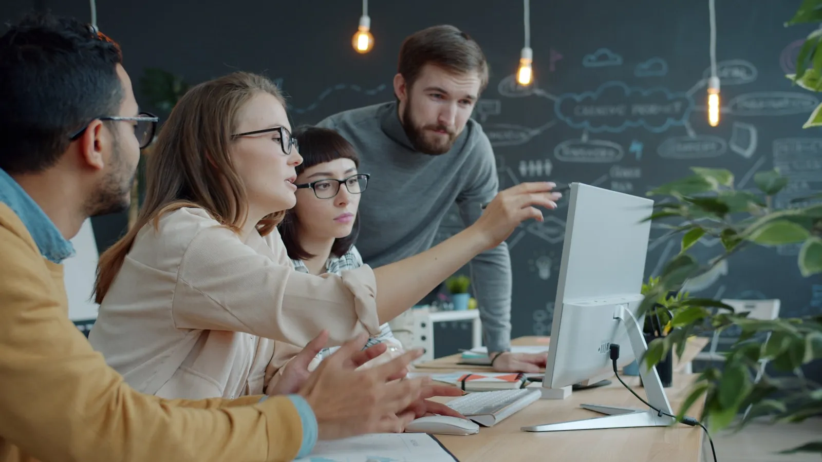 A team of engineers gathered around a monitor in an office, discussing their work.