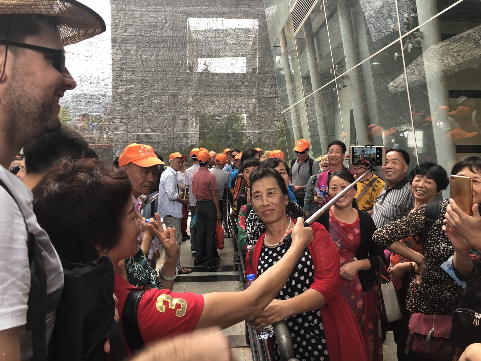 A crowd of local tourists in matching orange caps gathering to take photos with us